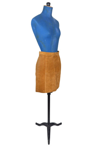 Vintage 1980s suede mini skirt in a light caramel brown colour. The skirt is constructed with a middle panel down the front, and darts in the back to add shape. The skirt closes in the back with a zipper and a snap closure at the waist, and is fully lined.