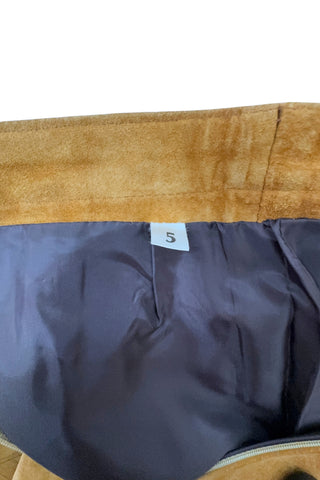 Vintage 1980s suede mini skirt in a light caramel brown colour. The skirt is constructed with a middle panel down the front, and darts in the back to add shape. The skirt closes in the back with a zipper and a snap closure at the waist, and is fully lined.