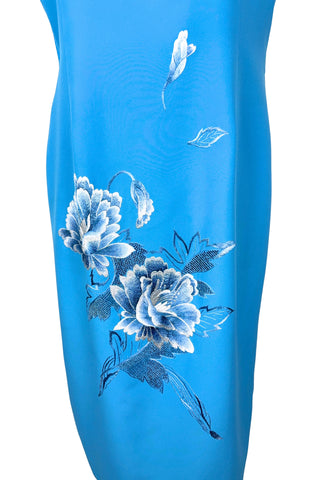 Vintage 1980s cheongsam dress in peacock blue with large white peony flower embroidery. The dress is sleeveless, with a mandarin collar, and closes with three frog closures across the chest, and a side zipper. The dress is unlined.