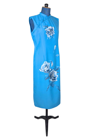 Vintage 1980s cheongsam dress in peacock blue with large white peony flower embroidery. The dress is sleeveless, with a mandarin collar, and closes with three frog closures across the chest, and a side zipper. The dress is unlined.
