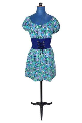 Vintage 1960s mini dress with laced bodice inspired by Alpine dirndl. The dress features a wide gathered neckline and puff sleeves, and closes in the back with a cotton twill zipper. It is made from green and blue floral print cotton with a wide navy blue bodice with silver crest buttons. The dress is unlined.