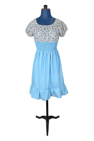 Vintage 1970s dress with adorable teacup and teapot print bodice with short puffed sleeves. The waist and skirt are sky blue, with a smocking style elasticized waist and a knee length skirt with wide ruffle hem. 
