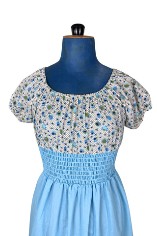 Vintage 1970s dress with adorable teacup and teapot print bodice with short puffed sleeves. The waist and skirt are sky blue, with a smocking style elasticized waist and a knee length skirt with wide ruffle hem. 