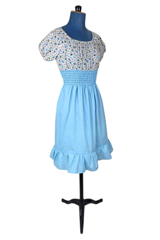 Vintage 1970s dress with adorable teacup and teapot print bodice with short puffed sleeves. The waist and skirt are sky blue, with a smocking style elasticized waist and a knee length skirt with wide ruffle hem. 