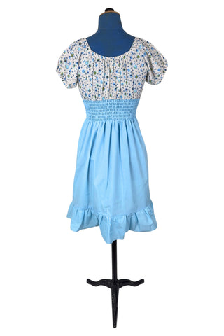 Vintage 1970s dress with adorable teacup and teapot print bodice with short puffed sleeves. The waist and skirt are sky blue, with a smocking style elasticized waist and a knee length skirt with wide ruffle hem. 