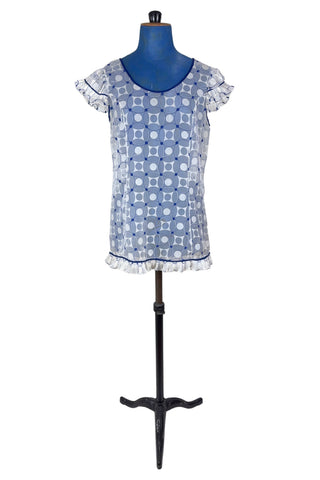 Vintage 1960s babydoll nightie in white and navy blue geometric ‘flowering snowball’ pattern. The white and blue pattern is printed onto sheer white chiffon, creating a 3D effect. The nightie has a wide round collar finished with navy blue piping, which is echoed at the hem and along the edges of the cap sleeves. The hem and sleeves are trimmed with delicate accordion pleated frills.