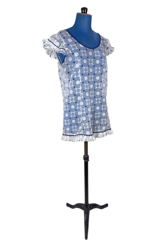 Vintage 1960s babydoll nightie in white and navy blue geometric ‘flowering snowball’ pattern. The white and blue pattern is printed onto sheer white chiffon, creating a 3D effect. The nightie has a wide round collar finished with navy blue piping, which is echoed at the hem and along the edges of the cap sleeves. The hem and sleeves are trimmed with delicate accordion pleated frills.