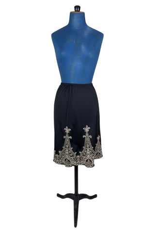 Vintage 1950s half slip in black with intricate cream corded lace decoration at the hem. The waist is elasticized.