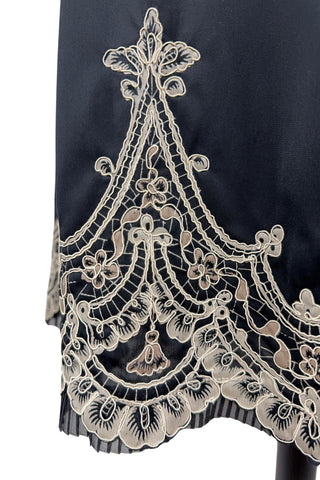 Vintage 1950s half slip in black with intricate cream corded lace decoration at the hem. The waist is elasticized.