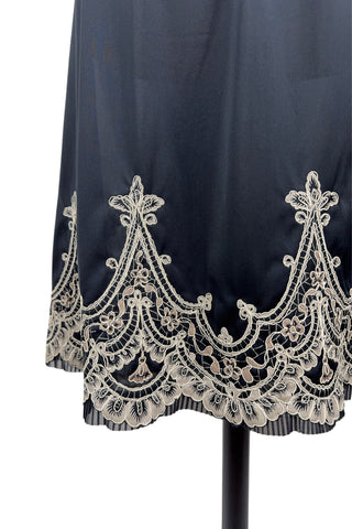 Vintage 1950s half slip in black with intricate cream corded lace decoration at the hem. The waist is elasticized.