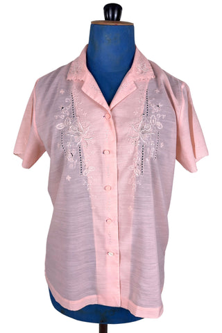 Vintage 1970s pink blouse with floral embroidery and covered buttons. Features short sleeves with scalloped edges, and an embroidered pointed collar.
