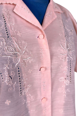 Vintage 1970s pink blouse with floral embroidery and covered buttons. Features short sleeves with scalloped edges, and an embroidered pointed collar.