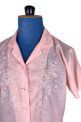 Vintage 1970s pink blouse with floral embroidery and covered buttons. Features short sleeves with scalloped edges, and an embroidered pointed collar.