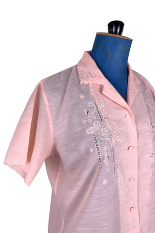 Vintage 1970s pink blouse with floral embroidery and covered buttons. Features short sleeves with scalloped edges, and an embroidered pointed collar.