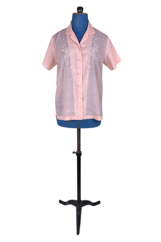 Vintage 1970s pink blouse with floral embroidery and covered buttons. Features short sleeves with scalloped edges, and an embroidered pointed collar.