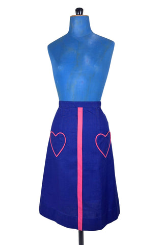 Vintage 1970s A-line skirt in navy blue cotton with pink heart shaped pockets and stripe down the front. Closes in the left side with four hook and eye closures.