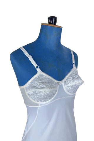 Vintage 1960s full slip with built-in bra. Designed as a close fitting foundation garment which provides a smoothing effect. The front and back panels of the skirt are made of 100% nylon, which gives more sturdy support, while the side panels and bra band have a nylon-spandex blend with more stretch to hug your curves.

Marked size 32 B.