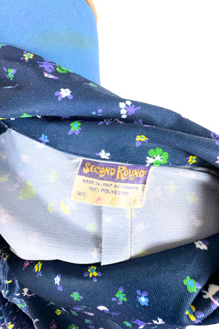 Vintage 1970s navy blue short sleeve A-line dress with tiny multicolour floral print. Closes with a zipper down the front.

Designed by Second Round. Made in Canada.