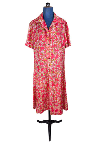 Vintage 1970s silk day dress in abstract ‘pebble’ print in shades of brown and pink on a pinkish red background. The dress has short sleeves, a wide pointed collar, and closes down the front with six flat gold metal buttons.