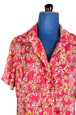 Vintage 1970s silk day dress in abstract ‘pebble’ print in shades of brown and pink on a pinkish red background. The dress has short sleeves, a wide pointed collar, and closes down the front with six flat gold metal buttons.