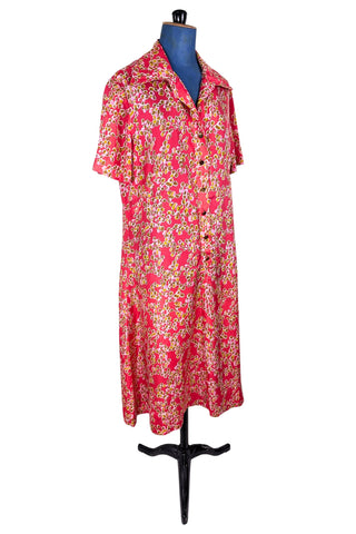 Vintage 1970s silk day dress in abstract ‘pebble’ print in shades of brown and pink on a pinkish red background. The dress has short sleeves, a wide pointed collar, and closes down the front with six flat gold metal buttons.