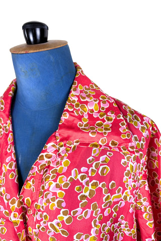 Vintage 1970s silk day dress in abstract ‘pebble’ print in shades of brown and pink on a pinkish red background. The dress has short sleeves, a wide pointed collar, and closes down the front with six flat gold metal buttons.