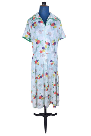 Vintage 1970s house dress in sky blue nylon jersey with a multicolour floral pansy print in red, yellow, purple, and white. The short sleeves and pointed collar are trimmed with grass green piping. Closes with a zipper down the front.

Designed by Windsor.