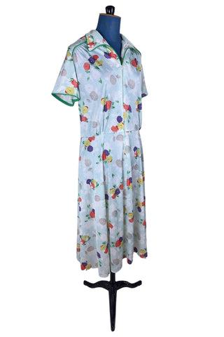 Vintage 1970s house dress in sky blue nylon jersey with a multicolour floral pansy print in red, yellow, purple, and white. The short sleeves and pointed collar are trimmed with grass green piping. Closes with a zipper down the front.

Designed by Windsor.