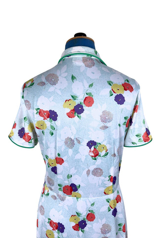 Vintage 1970s house dress in sky blue nylon jersey with a multicolour floral pansy print in red, yellow, purple, and white. The short sleeves and pointed collar are trimmed with grass green piping. Closes with a zipper down the front.

Designed by Windsor.