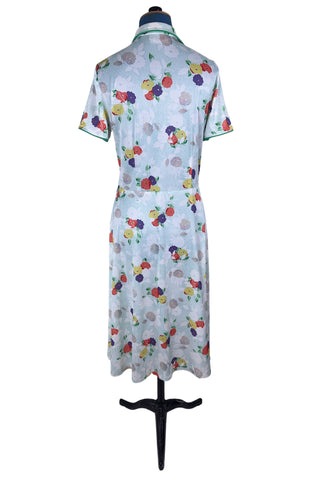 Vintage 1970s house dress in sky blue nylon jersey with a multicolour floral pansy print in red, yellow, purple, and white. The short sleeves and pointed collar are trimmed with grass green piping. Closes with a zipper down the front.

Designed by Windsor.