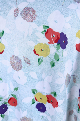 Vintage 1970s house dress in sky blue nylon jersey with a multicolour floral pansy print in red, yellow, purple, and white. The short sleeves and pointed collar are trimmed with grass green piping. Closes with a zipper down the front.

Designed by Windsor.