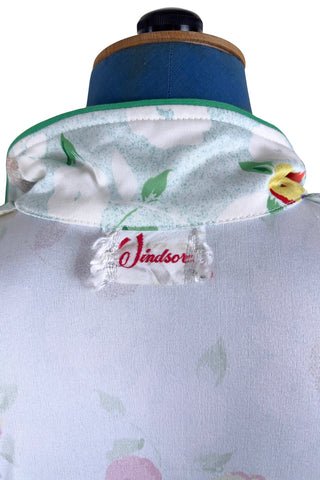 Vintage 1970s house dress in sky blue nylon jersey with a multicolour floral pansy print in red, yellow, purple, and white. The short sleeves and pointed collar are trimmed with grass green piping. Closes with a zipper down the front.

Designed by Windsor.