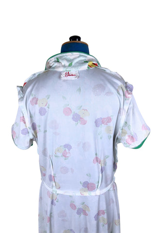 Vintage 1970s house dress in sky blue nylon jersey with a multicolour floral pansy print in red, yellow, purple, and white. The short sleeves and pointed collar are trimmed with grass green piping. Closes with a zipper down the front.

Designed by Windsor.