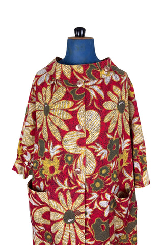 Vintage 1960s cotton robe with giant yellow and beige floral print on a red background. The housecoat features a wide standing collar, three quarter sleeves with slightly gathered buttoned cuffs, and large square pockets. Closes with five pearly buttons down the front, and one at the side of the collar.