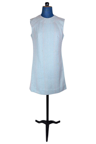 Simple and elegant vintage 1960s shift dress in light blue with a raised silver textured geometric pattern resembling fish or lizard scales. The sleeveless dress features a round collar and darts at the bust to add shape. The dress closes in the back with a cotton twill zipper, and is unlined.

This dress was made from a Vogue pattern, which would have included a Vogue Couturier Design label in the pattern package, intended to be added to the garment after sewing it from the pattern at home.