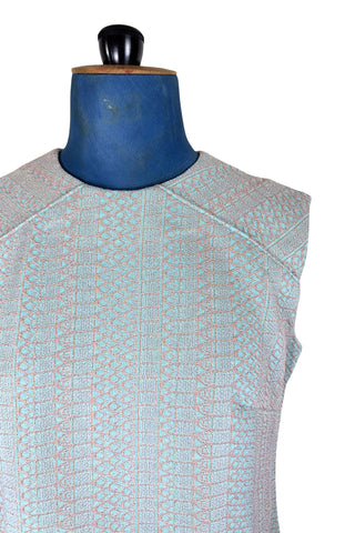 Simple and elegant vintage 1960s shift dress in light blue with a raised silver textured geometric pattern resembling fish or lizard scales. The sleeveless dress features a round collar and darts at the bust to add shape. The dress closes in the back with a cotton twill zipper, and is unlined.

This dress was made from a Vogue pattern, which would have included a Vogue Couturier Design label in the pattern package, intended to be added to the garment after sewing it from the pattern at home.