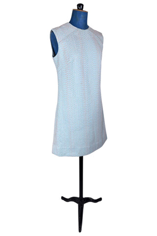 Simple and elegant vintage 1960s shift dress in light blue with a raised silver textured geometric pattern resembling fish or lizard scales. The sleeveless dress features a round collar and darts at the bust to add shape. The dress closes in the back with a cotton twill zipper, and is unlined.

This dress was made from a Vogue pattern, which would have included a Vogue Couturier Design label in the pattern package, intended to be added to the garment after sewing it from the pattern at home.