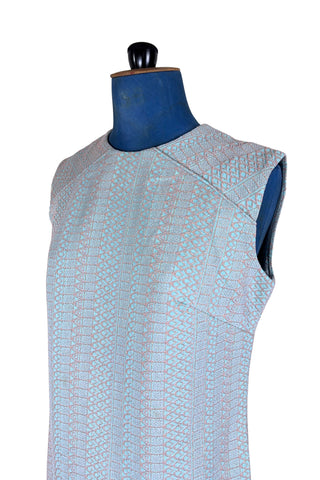 Simple and elegant vintage 1960s shift dress in light blue with a raised silver textured geometric pattern resembling fish or lizard scales. The sleeveless dress features a round collar and darts at the bust to add shape. The dress closes in the back with a cotton twill zipper, and is unlined.

This dress was made from a Vogue pattern, which would have included a Vogue Couturier Design label in the pattern package, intended to be added to the garment after sewing it from the pattern at home.