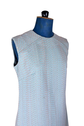Simple and elegant vintage 1960s shift dress in light blue with a raised silver textured geometric pattern resembling fish or lizard scales. The sleeveless dress features a round collar and darts at the bust to add shape. The dress closes in the back with a cotton twill zipper, and is unlined.

This dress was made from a Vogue pattern, which would have included a Vogue Couturier Design label in the pattern package, intended to be added to the garment after sewing it from the pattern at home.