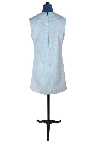 Simple and elegant vintage 1960s shift dress in light blue with a raised silver textured geometric pattern resembling fish or lizard scales. The sleeveless dress features a round collar and darts at the bust to add shape. The dress closes in the back with a cotton twill zipper, and is unlined.

This dress was made from a Vogue pattern, which would have included a Vogue Couturier Design label in the pattern package, intended to be added to the garment after sewing it from the pattern at home.