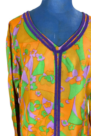 Vintage 1960s psychedelic print maxi dress in bright orange, green and purple abstract floral print, with purple soutache trim detail around the collar and down the front. The dress has long sleeves, and closes in the back with a metal zipper. 

Designed with an A-line silhouette which flares gently through the hips.