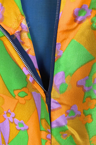 Vintage 1960s psychedelic print maxi dress in bright orange, green and purple abstract floral print, with purple soutache trim detail around the collar and down the front. The dress has long sleeves, and closes in the back with a metal zipper. 

Designed with an A-line silhouette which flares gently through the hips.