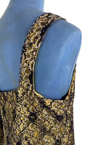 Vintage 1960s cocktail dress with sheer black lace layered over a bright yellow lining. The dress is sleeveless, with straps that narrow towards the back, and a wide, round neckline. Closes in the back with a cotton twill zipper.