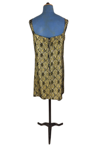 Vintage 1960s cocktail dress with sheer black lace layered over a bright yellow lining. The dress is sleeveless, with straps that narrow towards the back, and a wide, round neckline. Closes in the back with a cotton twill zipper.