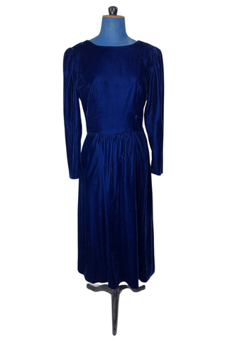 Vintage 1970s Lanz Originals blue velvet cocktail dress in 100% rayon. The dress features long sleeves which are slightly puffed at the lightly padded shoulders. The skirt is gathered into the bodice, with the gathering more concentrated towards the front and back. Long vertical seams in the bodice add shape. The back of the dress has a lovely and unexpected triple bow detail on the deep V-cut back.

Designed by Lanz Originals. Made in U.S.A.

Marked size 6. Fits like a small to medium.