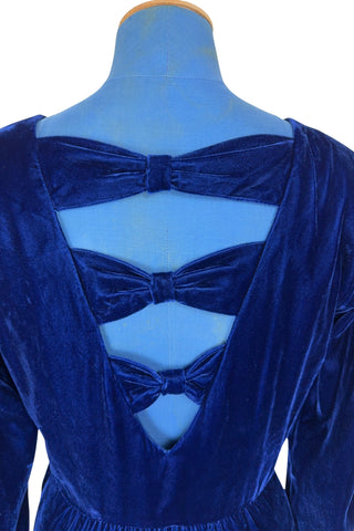 Vintage 1970s Lanz Originals blue velvet cocktail dress in 100% rayon. The dress features long sleeves which are slightly puffed at the lightly padded shoulders. The skirt is gathered into the bodice, with the gathering more concentrated towards the front and back. Long vertical seams in the bodice add shape. The back of the dress has a lovely and unexpected triple bow detail on the deep V-cut back.

Designed by Lanz Originals. Made in U.S.A.

Marked size 6. Fits like a small to medium.