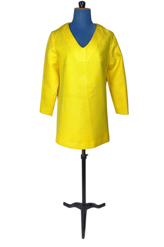 Vintage 1960s mod mini dress in bright yellow textured heavyweight cotton. The textured weave has a small circular motif that resembles bubbles. The dress features a V neckline, long sleeves, and closes in the back with a metal zipper.