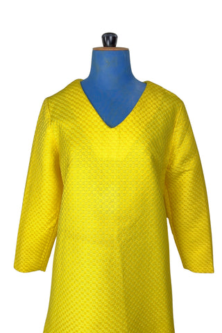 Vintage 1960s mod mini dress in bright yellow textured heavyweight cotton. The textured weave has a small circular motif that resembles bubbles. The dress features a V neckline, long sleeves, and closes in the back with a metal zipper.