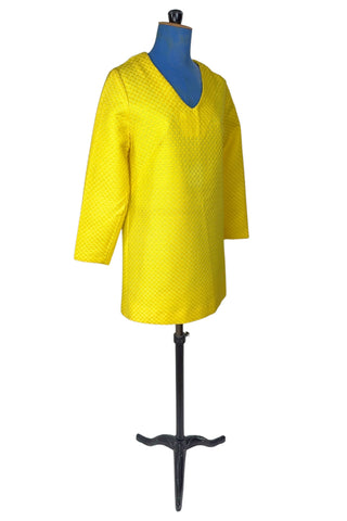 Vintage 1960s mod mini dress in bright yellow textured heavyweight cotton. The textured weave has a small circular motif that resembles bubbles. The dress features a V neckline, long sleeves, and closes in the back with a metal zipper.