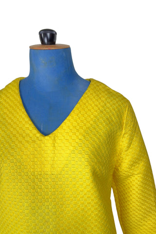 Vintage 1960s mod mini dress in bright yellow textured heavyweight cotton. The textured weave has a small circular motif that resembles bubbles. The dress features a V neckline, long sleeves, and closes in the back with a metal zipper.